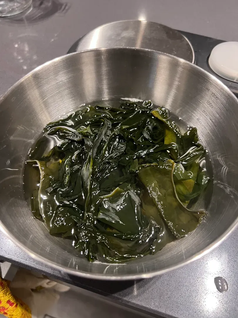 Kombu soaking in water in a steel bowl